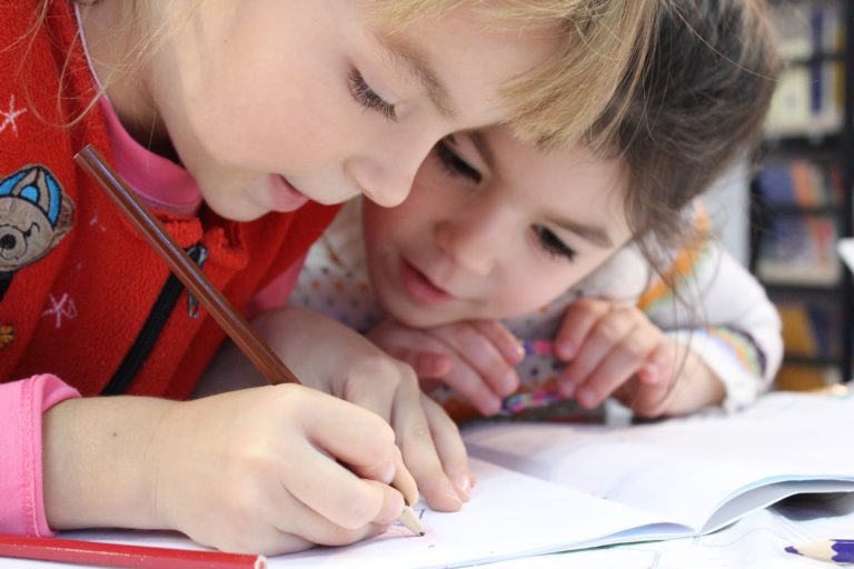 girls-on-desk-looking-at-notebook-159823